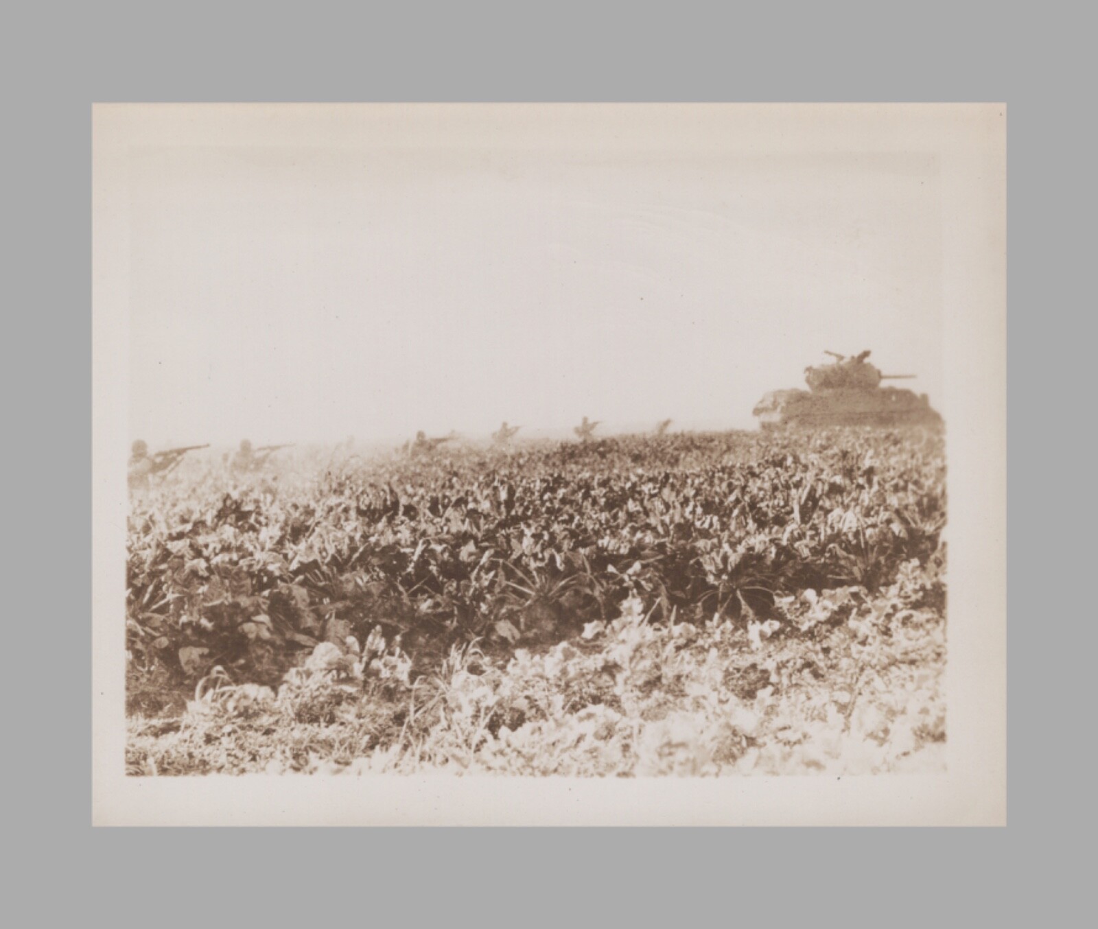 WW2 Photo U.S. GIs Walking Spaced Apart Guns Out Behind Military Tank In Field